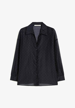 Chemise noire à manches longues avec petits pois blancs, col classique et manches à poignets, présentée sur fond blanc.