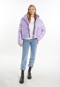 Lavendel pufferjakke med høj krave, to forlommer og en blank tekstur. Sammen med lyseblå jeans og sorte ankelstøvler.