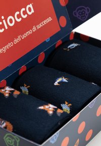 Marine sokken in een doos met rode stippen. Bevat speelse dierenpatronen in oranje, wit en blauw, gemaakt van zacht en flexibel materiaal.