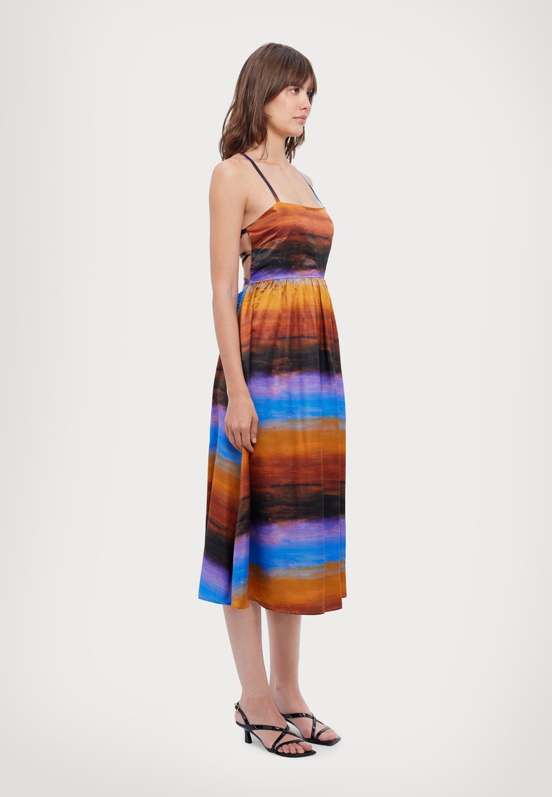 Maxi kjole i multicolor gradient med nuancer af orange, blå og lilla. Spaghetti stropper, tætsiddende bodice og svajende nederdel.