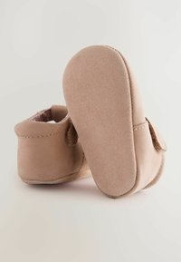 Bottines pour bébés en suède beige avec une bande auto-agrippante, bout rond, doublure douce et semelle flexible et texturée.