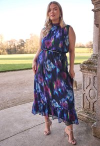 Abito lungo in tessuto blu navy scuro con motivi floreali colorati. Presenta un orlo a balze, una vita aderente con un nastro coordinato e un design senza maniche.