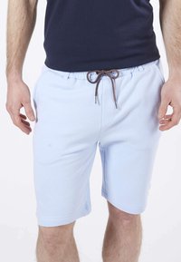 Shorts bleu clair avec une ceinture élastique, featuring un cordon de serrage marron et des poches latérales, fabriqués en tissu doux et lisse.