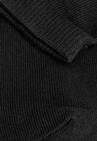Schwarzer Strickstoff mit geripptem Muster und umgeschlagenem Rand. Das Material fühlt sich weich und flexibel an, geeignet für Bekleidungsartikel.