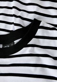 Sort og hvid stribet t-shirt med en sort rund udskæring. Stoffet ser blødt ud med en glat tekstur. 'LMTD' mærket er synligt indeni kraven.