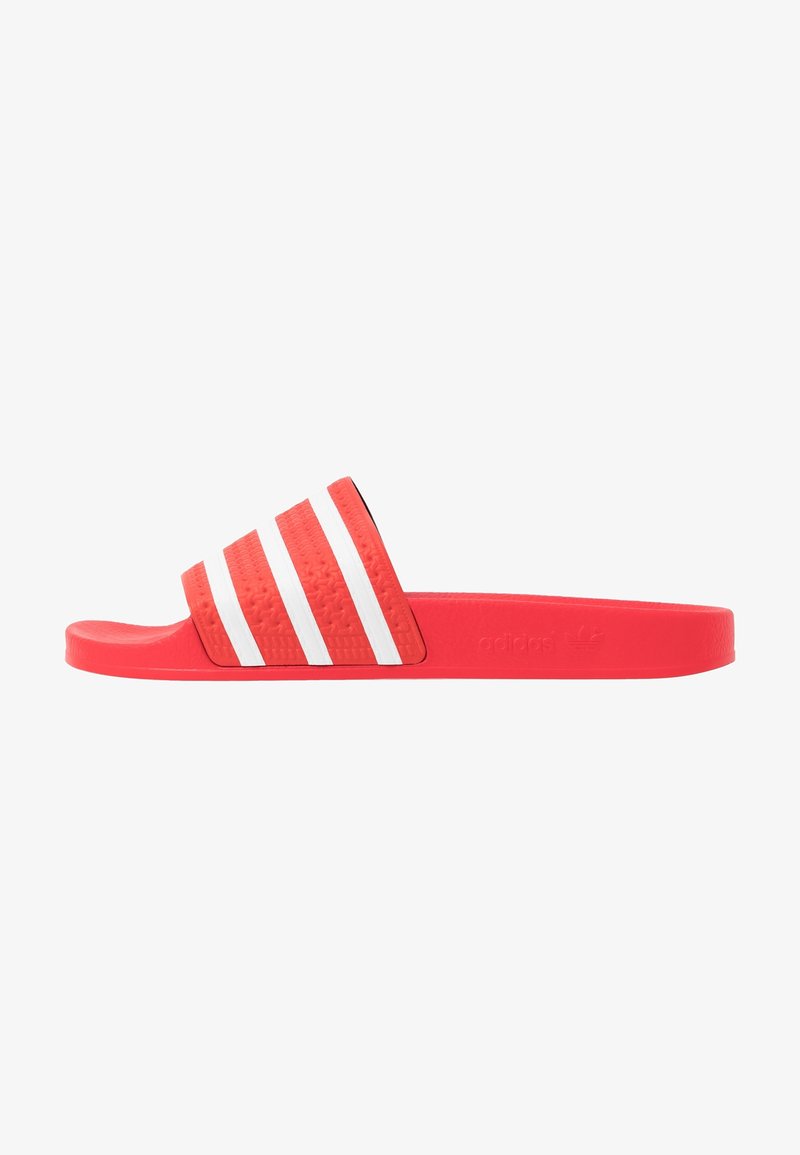 Červené skluzavkové sandály vyrobené z gumy, s texturovaným popruhem se třemi bílými pruhy a tvarovanou stélkou. Zdůrazněno logem Adidas.