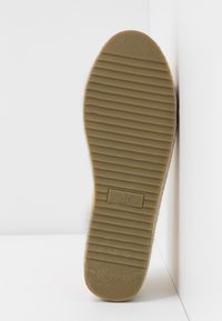 Sål af en sko med en tekstureret, rillede overflade i beige gummi. Størrelse 37 er angivet på bunden. Designet er fladt med minimale accenter.