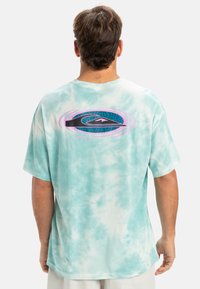 Short-sleeve t-shirt in light turquoise tie-dye pattern. Features a graphic design with black, pink, and blue accents on the back.