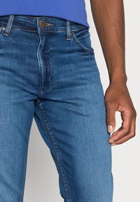 Blauwe spijkerbroeken met een classic fit, vijf zakken, koperen stiksels en een rits met een knoopsluiting aan de voorkant.