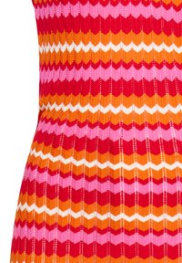 Tessuto lavorato a maglia con motivo a chevron in rosso, rosa, arancione e bianco, dall'aspetto texture e larghezze variabili.