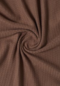 Tissu marron texturé avec un motif en chevrons, présentant une texture douce et légèrement duveteuse. Le tissu est torsadé, mettant en avant sa souplesse.