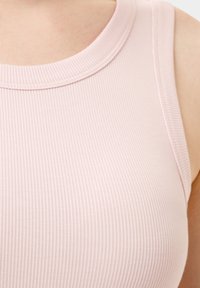 Top de tirantes de color rosa claro, con escote redondo y diseño sin mangas, que presenta una textura sutil y detalles de costura a lo largo de los bordes.