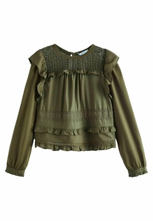 Blouse à manches longues vert olive avec détails en dentelle, accents volantés et ourlet froncé. Dotée d'un col rond et d'une ouverture en forme de goutte dans le dos.
