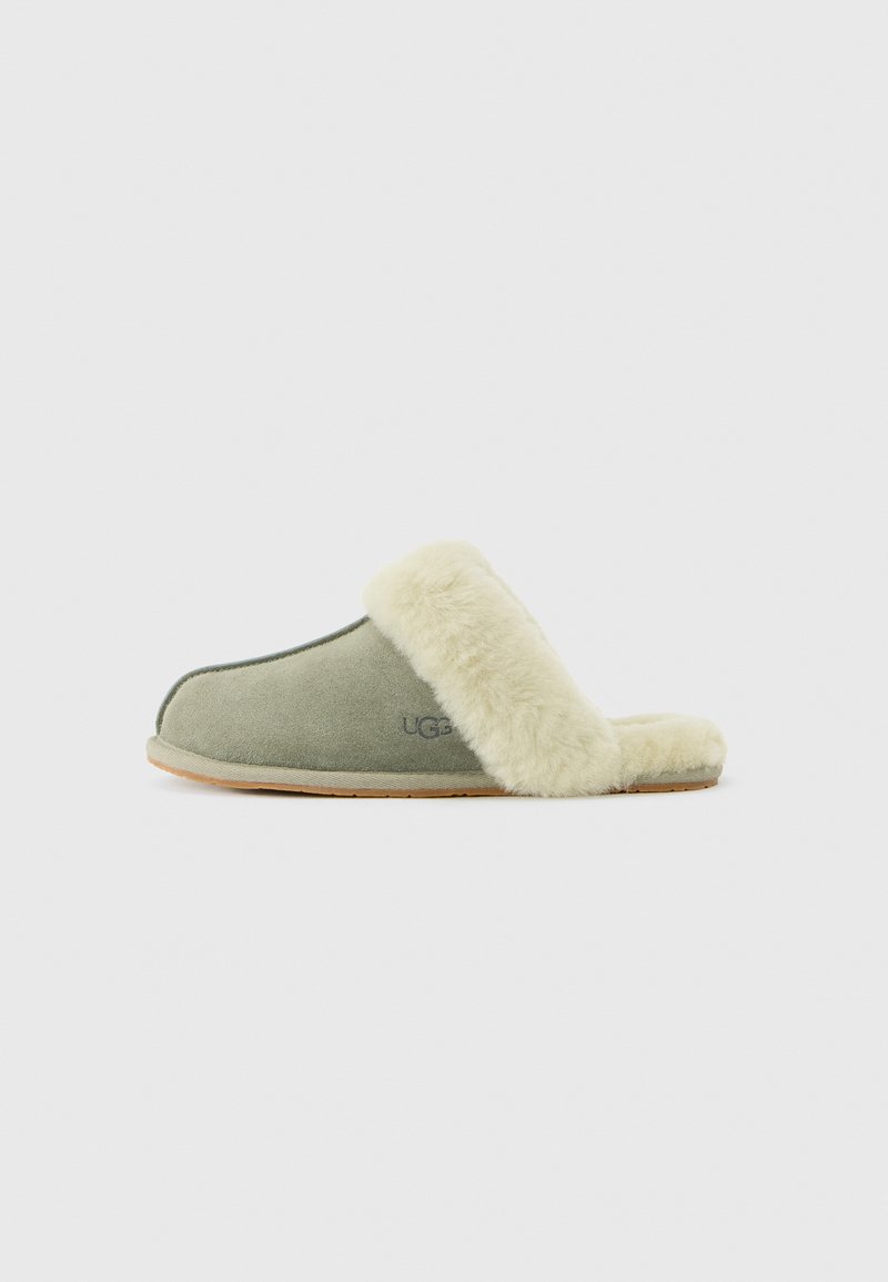 Zachte groene suede slof met een crèmekleurige pluche voering en afwerking, voorzien van het UGG-logo aan de zijkant, met een platte zool.