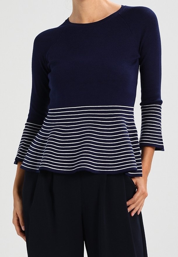 Top péplum bleu marine à manches trois-quarts, avec une section inférieure rayée en blanc et bleu marine. Confectionné dans un tissu côtelé.