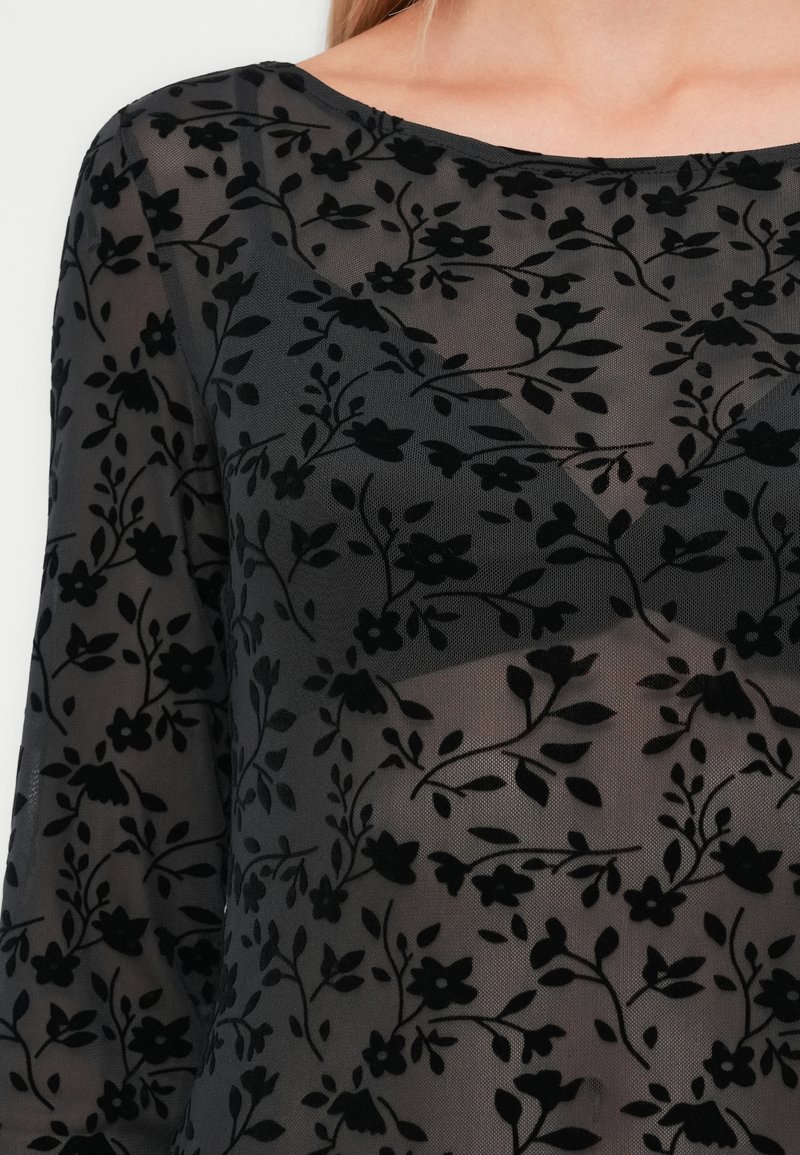 Schwarzes transparentes Oberteil mit floralem Muster aus strukturiertem Stoff, mit langen Ärmeln und rundem Ausschnitt.