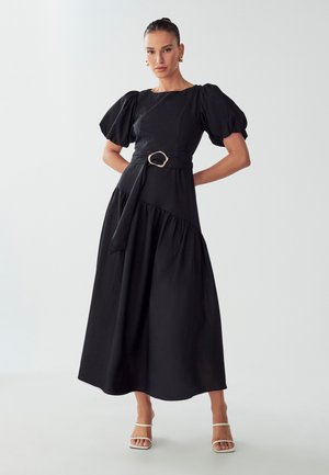 Robe midi noire en tissu léger, avec des manches courtes bouffantes, un corsage ajusté et une taille ceinturée avec un détail de boucle en ton or.