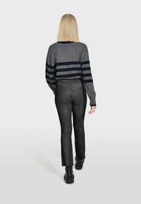 Sivi pleteni pulover s mornarskim prugama, uparen s uskim crnim kožnim hlačama. Glatka tekstura s elastičnom pasicom, naglasci s niskim čizmama.