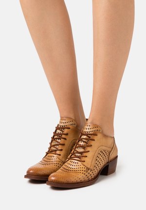 Chaussures en cuir marron clair avec fermeture à lacets, design perforé, petit talon carré et motifs texturés sur l'avant et le côté.