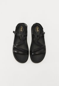 Zwarte sandalen met kruiss banden, gemaakt van synthetisch materiaal. Voorzien van een gespband en cushioning op de binnenzool voor comfort.