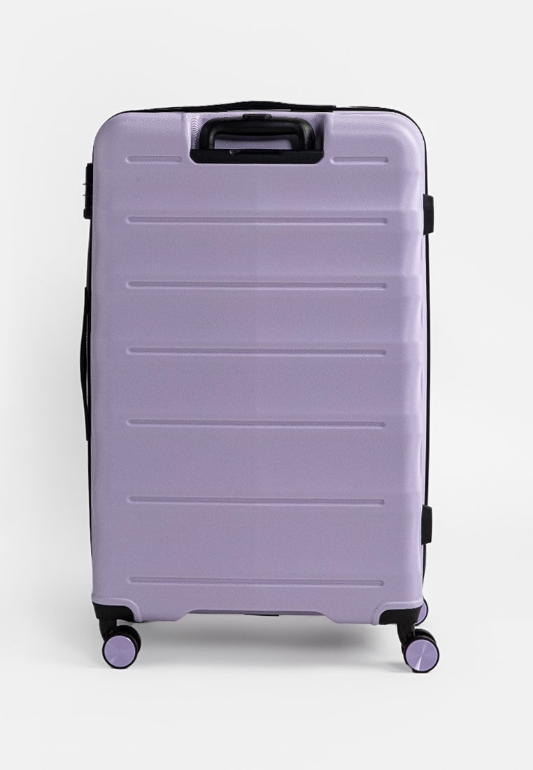 Valise rigide violette avec des rainures horizontales, deux roues à roulement fluide, une poignée supérieure et des accents de fermeture éclair noirs.