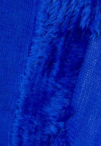 Blå textil med en kombination av slätstickade och plyschiga strukturer, med en livfull blå färg genomgående, som framhäver variationer i mjukhet.