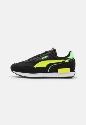 Czarne buty sportowe Puma z neonowo żółtymi i zielonymi akcentami, białą miękką podeszwą, teksturowaną czarną podeszwą zewnętrzną i zapięciem na sznurowadła, pokazane z boku.