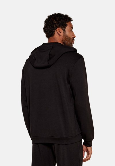Sudadera negra con capucha ajustable, mangas largas y un corte relajado con puños y dobladillo acanalados. Textura suave y un diseño minimalista.
