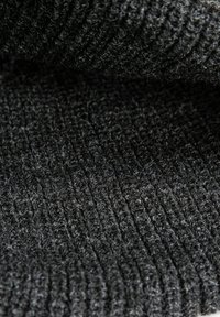 Nahaufnahme von dunkelgrauem Strickstoff mit gerippter Textur und sichtbaren Schlaufen und Fasern.
