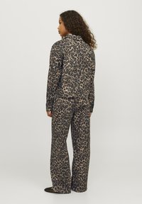 Sada kabátu a kalhot s leopardím vzorem, s tmavým základem a béžovými skvrnami, vyrobená z hladkého materiálu, s volným střihem a dlouhými rukávy.