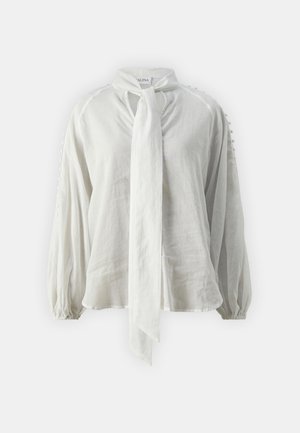 Bijela, lagana bluzica s vezicom oko vrata, balon rukavima i teksturiranim detaljima na ramenima. Napravljena od mekog, prozračnog materijala.