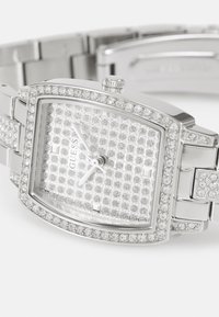 Orologio da uomo Silver Guess con cassa rettangolare, lunetta adornata di cristalli, quadrante testurizzato e bracciale in metallo, caratterizzato da finiture lucide e chiusura a deployante.