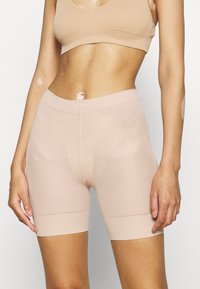 Nude sömlösa shorts gjorda av elastisk tyg. Har en elastisk midja och en slät textur med minimala sömnadsdetaljer.