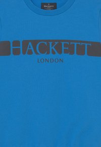 Modrá bavlněná mikina s černým logem "HACKETT" na hrudi a textem "LONDON" pod ním. Kulatý výstřih, měkká textura.