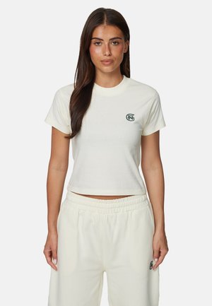 Maglietta corta color crema in tessuto morbido con scollo rotondo e maniche corte. Presenta un piccolo logo nero sul petto.