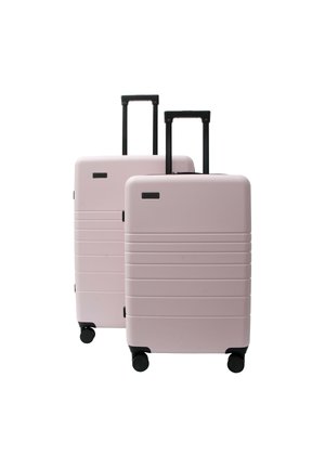 Two light pink hard-shell suitcases with black handles and four wheels, one slightly larger than the other, standing upright.