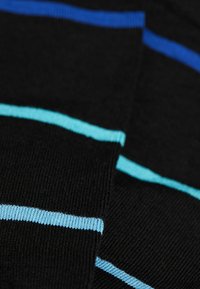 Sort stof med vandrette striber i lyseblå og mørkeblå. Teksturen er glat og ribbet med et strikket design.