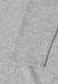 Texturerad grå och vit tyg med ett zigzag-mönster, med en mjuk, stickad känsla och synliga sömmar.