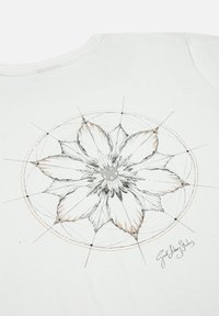 Witte t-shirt met een gedetailleerd zwart en oranje bloemenontwerp met geometrische elementen en de handtekening van de artiest onderaan.