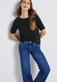 T-shirt en coton noir à manches courtes, col rond, associé à un jean en denim bleu taille mi-haute, coupe décontractée. Design simple et classique.