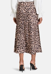 Leopardenmuster Midi-Rock aus einem glatten Stoff, mit einem fließenden Design und einem subtilen Glanz, kombiniert mit schwarzen, hochhackigen Riemchenschuhen.