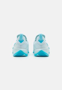 Light blue athletic shoes with a textured upper, contrasting darker blue accents, rear pull tabs, and patterned soles for grip.