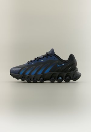 Zapatilla deportiva negra y azul con suela segmentada única, diseño con cordones y pequeño logo de Nike en el lateral y la lengüeta, mostrada sobre un fondo neutro.
