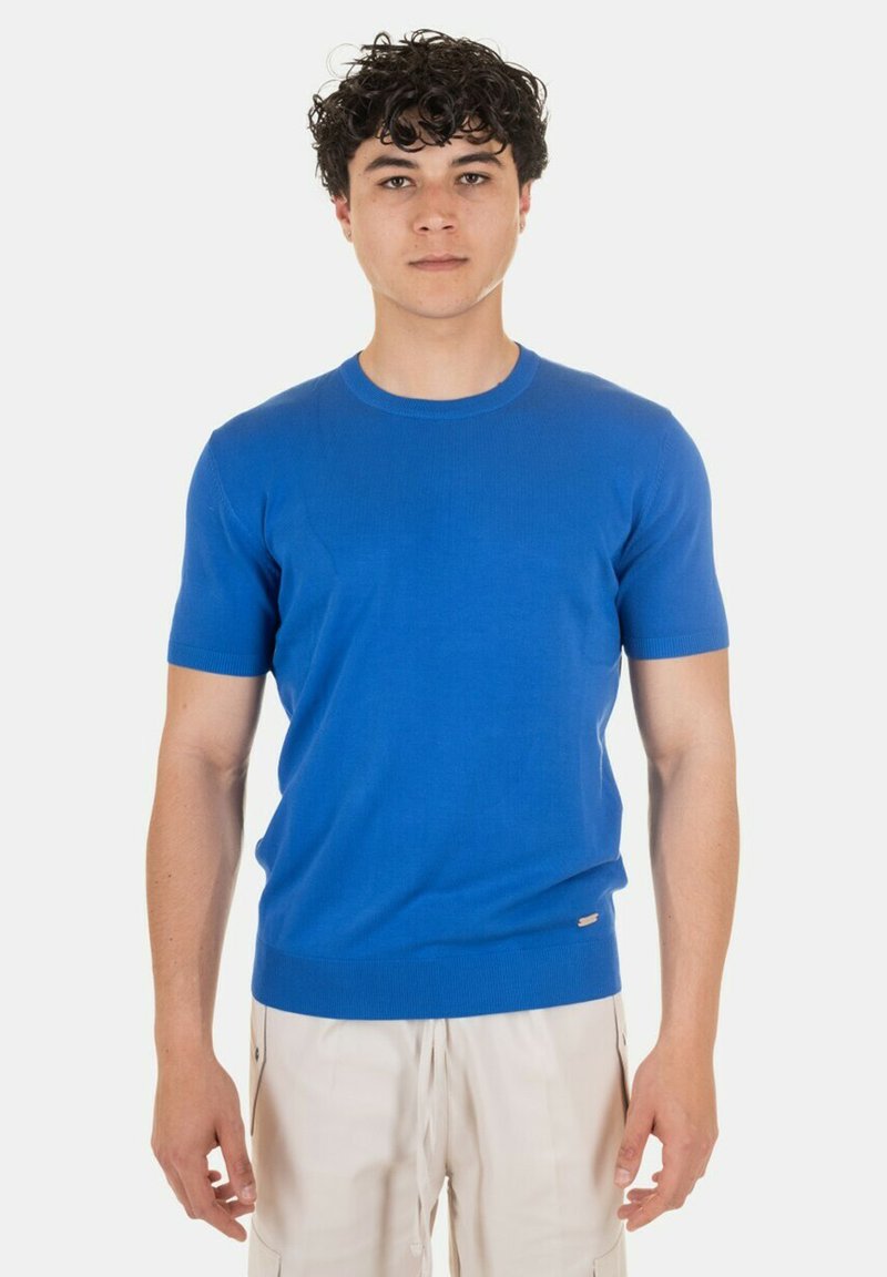 Maglione lavorato a maglia blu a maniche corte con collo rotondo, caratterizzato da una texture a coste e un sottile dettaglio del logo all'orlo. Silhouette a vestibilità diretta.