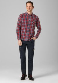 Red and blue plaid button-up shirt with a chest pocket, paired with dark cargo pants featuring side pockets, and black boots with red laces.