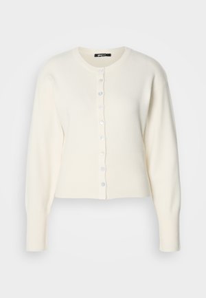 Bijela pletena kardigan s rebrastim rubom i dugim rukavima, s okruglim izrezom i redom plavih dugmadi sprijeda.