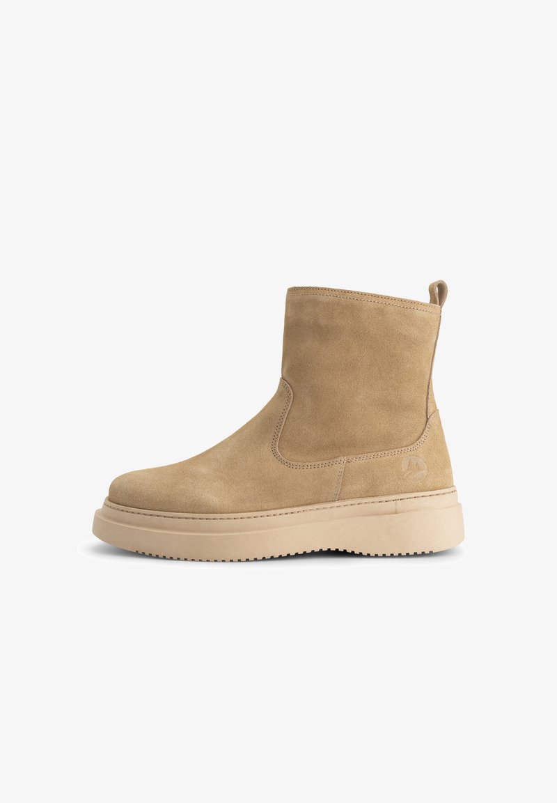 Beige suede ankle boot with thick beige rubber sole, pull tab at back, and subtle logo embossing on side.