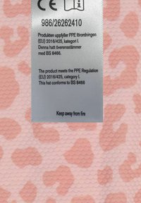 Ruusu-kuvioinen kangas, jossa on teksturoitu pinta ja turvalogo. Tunniste ilmoittaa EU:n PPE-sääntöjen noudattamisesta ja paloturvallisuusohjeista.