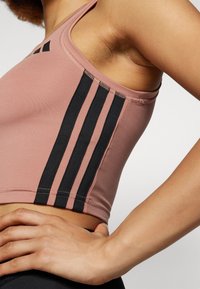 Mørk rosa sports crop top med svarte sidestriper, med en myk tekstur, racerback-design og sømmer som er sydd.