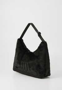 Svart faux fur skulderveske med glatt tekstur, halvsirkelform og justerbar svart stropp. Har et minimalistisk design.